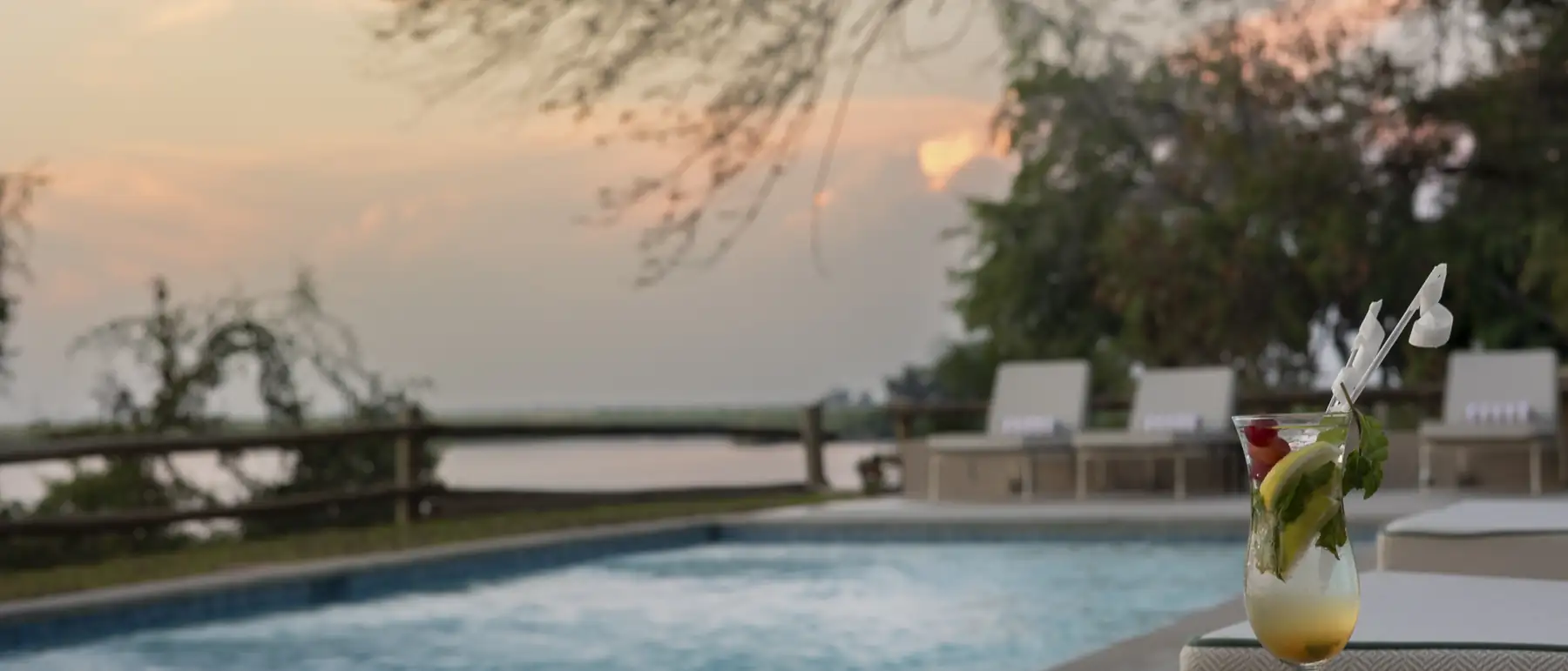 A cocktail beside the river-facing pool at sunset