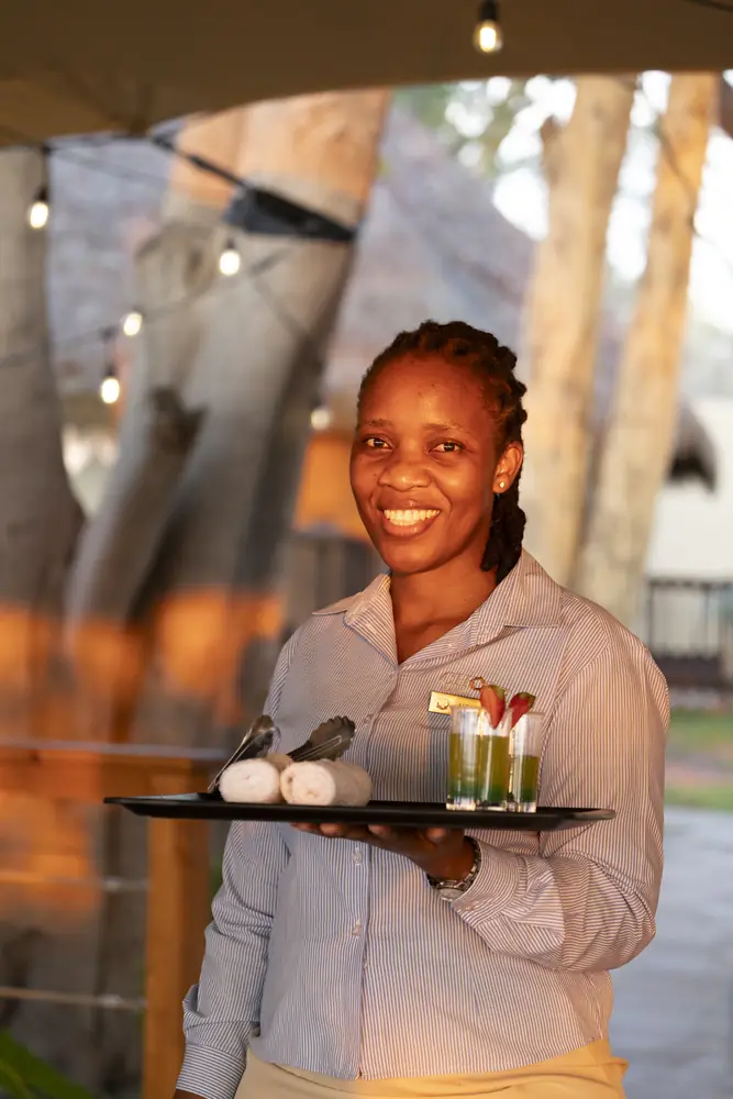 A smiling host holding a tray of welcome drinks